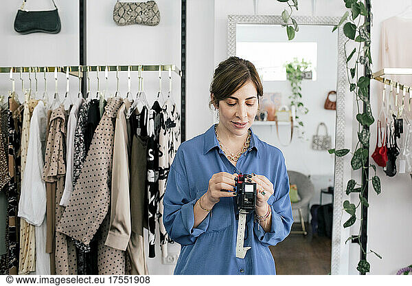 Mid adult female entrepreneur holding measuring tape at boutique