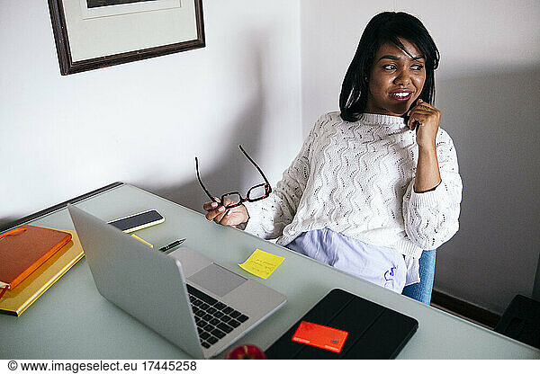 Mid adult female freelancer sitting with laptop at desk
