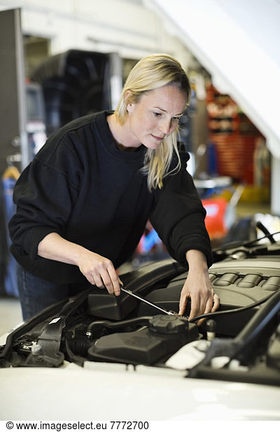 Mid adult female mechanic repairing car engine at workshop