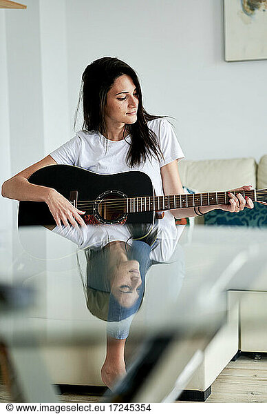 Mid adult Frau spielt Gitarre zu Hause