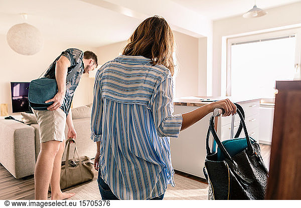 Mid adult man and woman with luggage in apartment