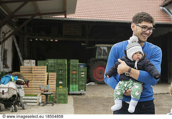 Mid adult man carrying his son and smiling  Bavaria  Germany