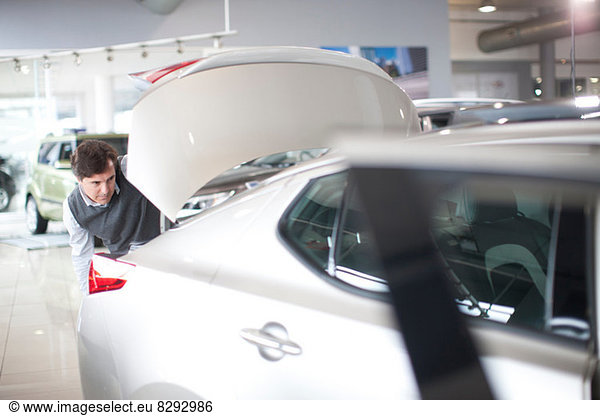 Mid adult man checking car boot in car showroom