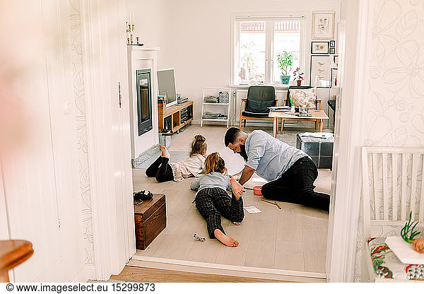 Mid adult man drawing with daughters while resting in living room at home