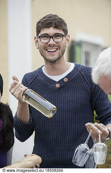 Mid adult man holding white wine and wine glasses  Bavaria  Germany