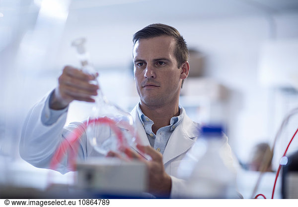 Mid adult man in laboratory  holding test tube