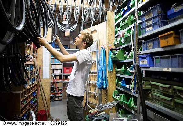 Mid adult man in repair shop choosing bicycle tyre