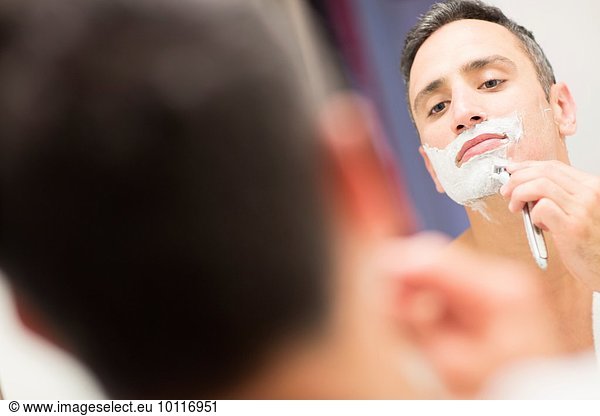 Mid adult man  looking in mirror  shaving