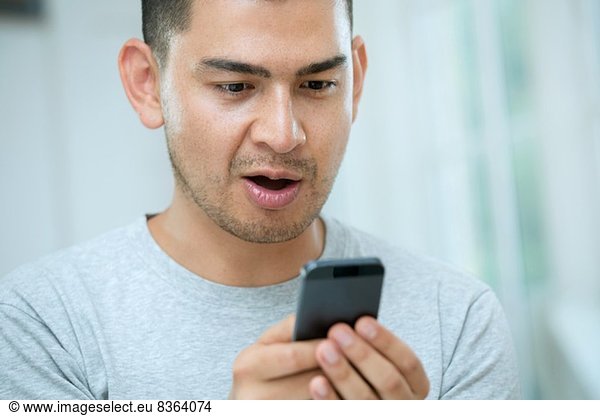 Mid adult man looking surprised at smartphone