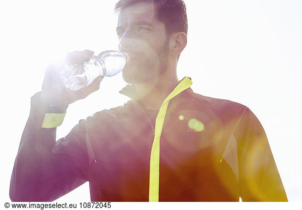 Mid adult man outdoors  drinking from water bottle