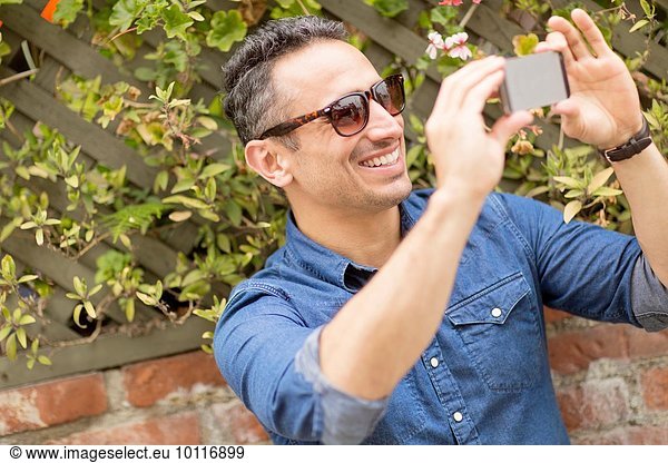 Mid adult man  outdoors  taking self portrait with smartphone