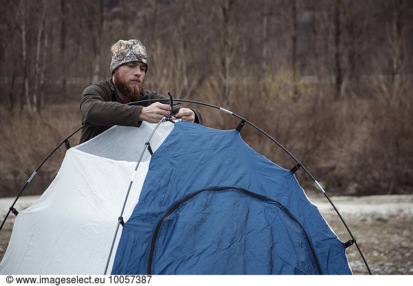 Mid adult man putting up tent