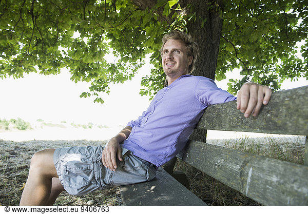 Mid adult man sitting on bench  smiling