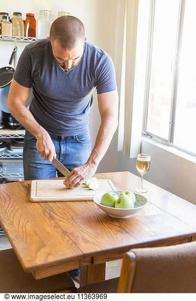 Mid adult man slicing apple at kitchen table