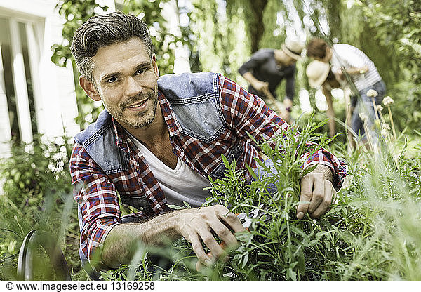 Mid adult man tending to plants in garden