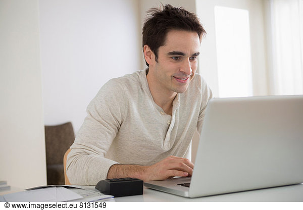 Mid adult man using laptop  smiling
