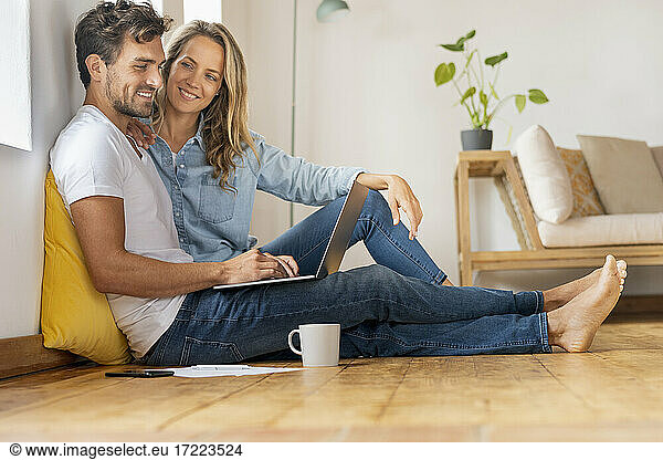 Mid adult man using laptop while sitting with girlfriend at home office