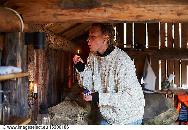 Mid adult woman blowing matchstick while standing in cottage