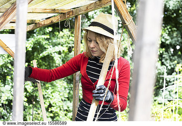 Mid adult woman constructing wooden shelter in her garden