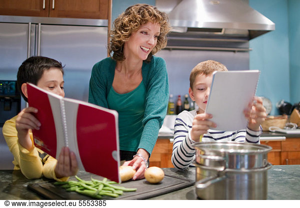 Mid adult woman cooking in kitchen with sons