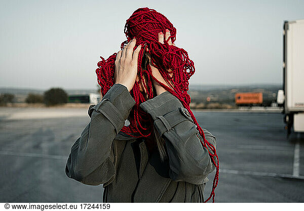 Mid adult woman covering face with thread standing on road