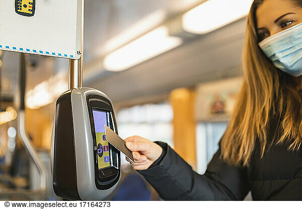 Mid adult woman doing contactless payment while commuting through tram