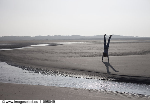 Mid adult woman doing handstand on beach  Renesse  Schouwen-Duiveland  Zeeland  Netherlands
