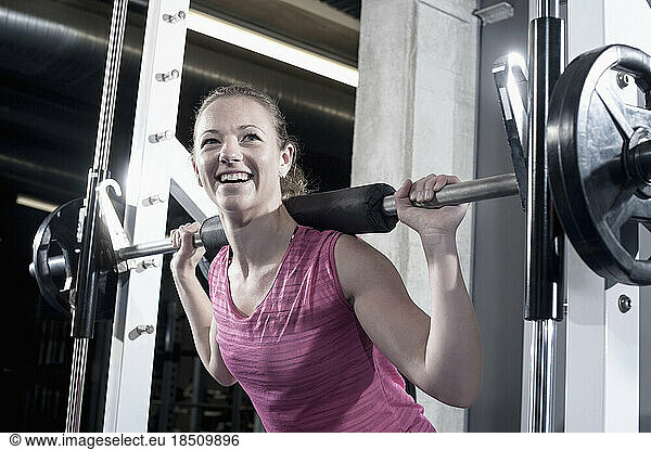 Mid adult woman doing squats barbell on her shoulders in the gym  Bavaria  Germany