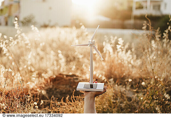 Mid adult woman holding wind turbine model