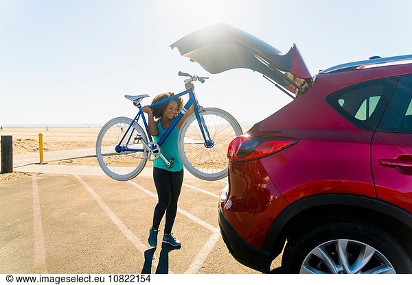 Mid adult woman putting bicycle into car boot