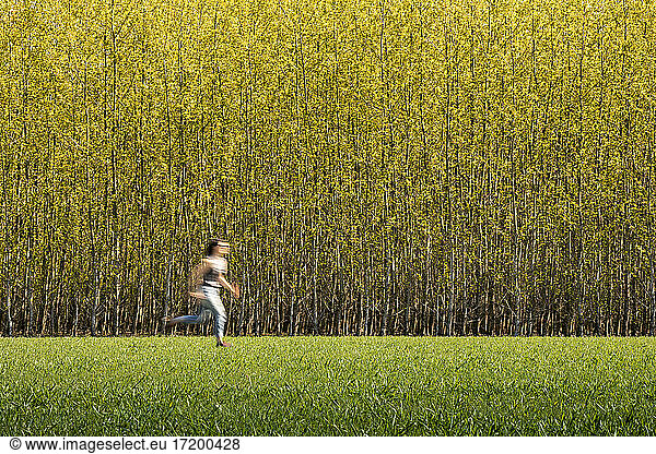 Mid adult woman running by tree farm