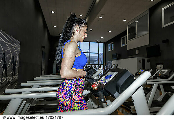 Mid adult woman running on treadmill in gym