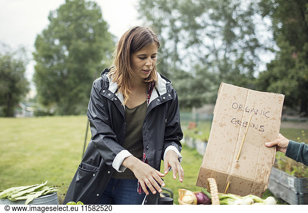 Mid adult woman standing by sign in vegetable garden