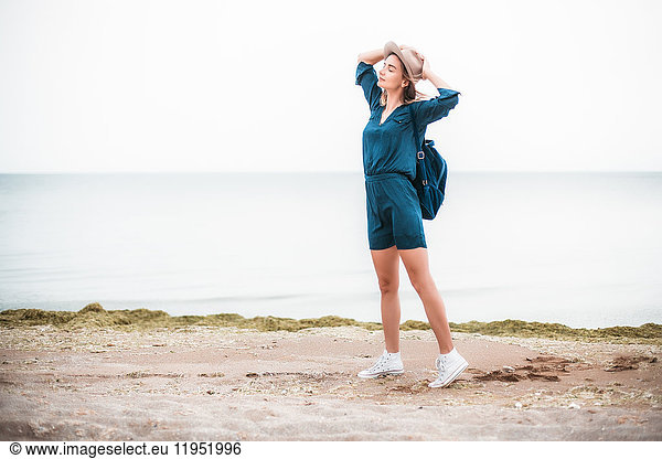 Mid adult woman standing near coastline  breathing in fresh air