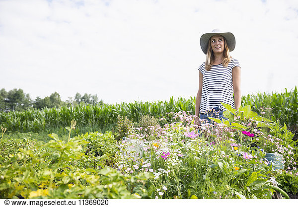 Mid adult woman standing with flowers in her community garden