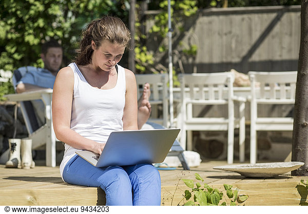 Mid adult woman using laptop on terrace