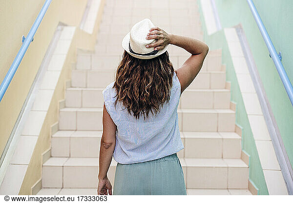 Mid adult woman wearing hat while standing on staircase