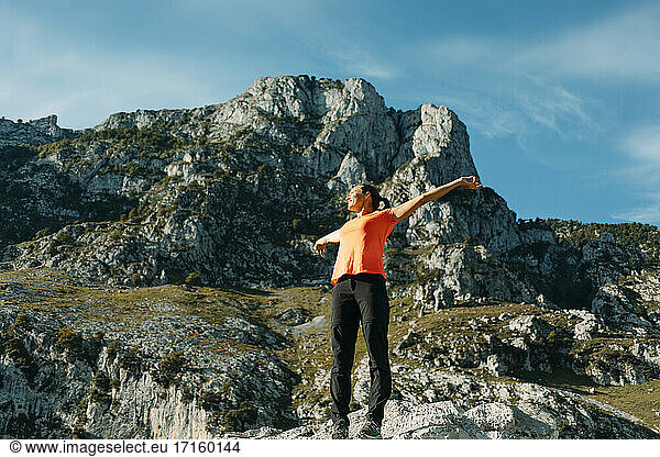 Mid adult woman with arms outstretched standing against mountain at Cares Trail in Picos De Europe National Park  Asturias  Spain