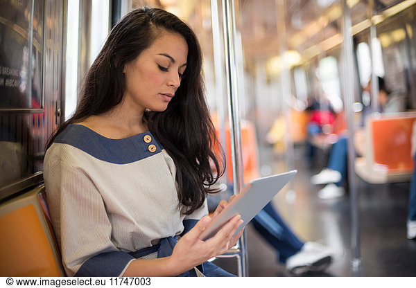 Mid adult women using digital tablet on subway New York