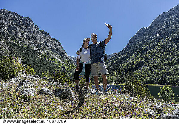 Mid aged tourist couple take selfie picture on the Spanish Pyrenees mountain with mobile