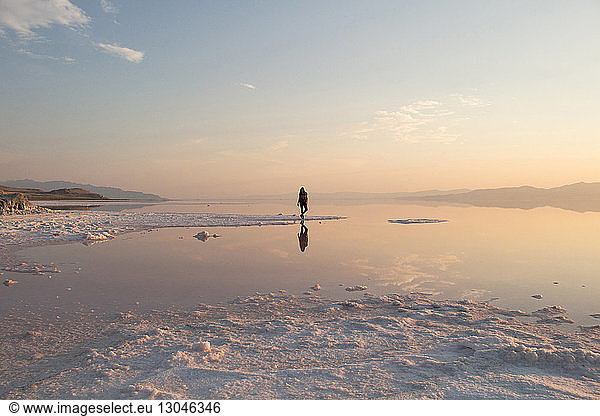 Mid distance of woman standing at Great Salt Lake during sunset