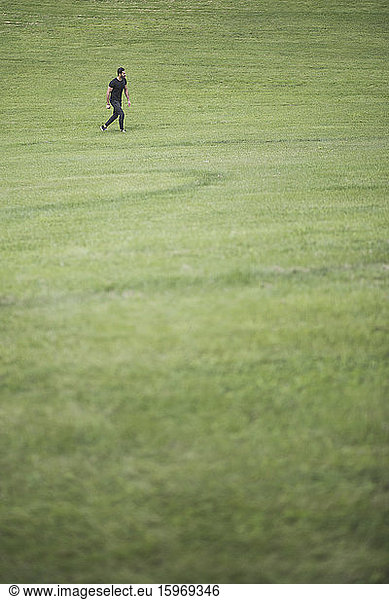 Mid distance view of man in casual clothing walking over grassy land