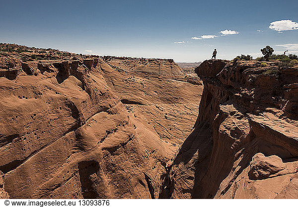 Mid distance view of man standing on cliff at Grand Staircase-Escalante National Monument against sky