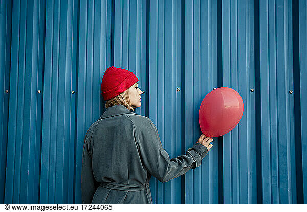 Mid erwachsene Frau hält roten Ballon durch blaue Blende