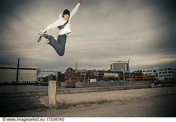Mid erwachsenen Mann mit Skateboard springen gegen Himmel