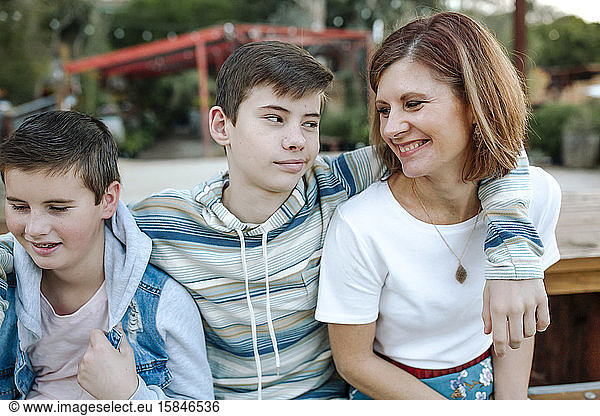 Mid-40's mom smiling at clean-cut teen and preteen sons
