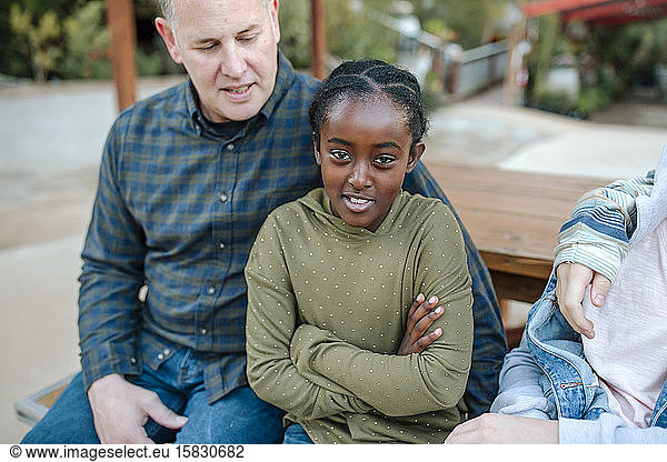 Mid-40's white dad sitting with smiling 8-yr-old black daughter