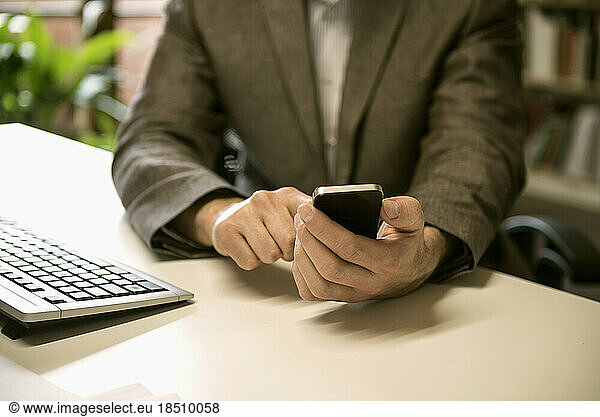 Mid section of a businessman using smart phone in an office  Bavaria  Germany