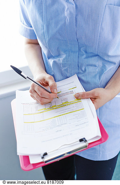 Mid-section of nurse writing paperwork