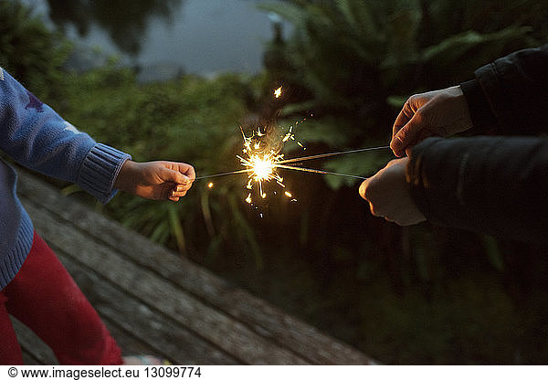 Mid section of people playing with sparklers at night